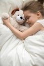 Little girl sleep hugging teddy bear in white bedroom