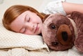 Little girl sleeping in bed hugging the teddy bear