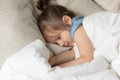 Little girl sleeping in bed under warm duvet closeup view