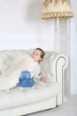 Little girl sleeps under white skin on white sofa