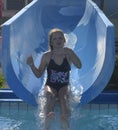 A little girl is sliding down on a flume into plunge pool at water park. Funny children attraction at water park Royalty Free Stock Photo