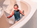 Little girl sliding down the water slide in aqua park children playground Royalty Free Stock Photo