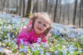 Little girl is smelling flowers while sitting on green meadow Royalty Free Stock Photo