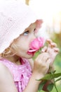 Little girl smelling pink rose