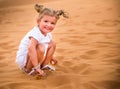 Little girl smiles and plays sand