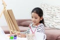 The little girl smiling and draws a picture at home