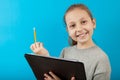 Little girl smiling looking and holding folder with paper and pencil in her hands. Portet on blue background Royalty Free Stock Photo