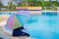 Little girl smiling near in swimming pool and holding colourful umbrella in hands. children playing in swimming pool on summer Royalty Free Stock Photo