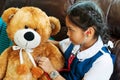 Little girl is smiling and playing doctor with brown bear and stethoscope. Kid and health care concept.