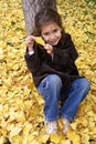 little girl smiling seated in yellow leaves