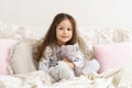 Little girl smiling with sleepy eyes and hugging favorite stuffed toy. Resting on cozy bed, waking up at morning. Royalty Free Stock Photo