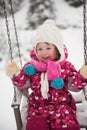 Little girl at snowy winter day swing in park Royalty Free Stock Photo