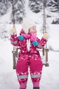 Little girl at snowy winter day swing in park Royalty Free Stock Photo