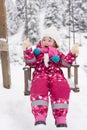 Little girl at snowy winter day swing in park Royalty Free Stock Photo