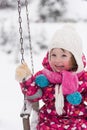 Little girl at snowy winter day swing in park Royalty Free Stock Photo