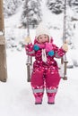 Little girl at snowy winter day swing in park Royalty Free Stock Photo