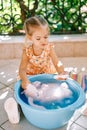 Little girl soaping up a soft toy in a bowl on the balcony Royalty Free Stock Photo