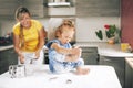 A little girl, soiled in flour, sits on the table and laughs. A girl plays with flour. Blurred background, space for text