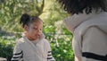 Little girl spending time with mother sitting on bench green garden close up. Royalty Free Stock Photo