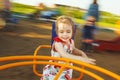 Little girl spinning on a children`s carousel among the playground. Royalty Free Stock Photo