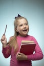 Little girl with a stack of books and a pencil in her hands on a blue background. Back to school and education concept Royalty Free Stock Photo