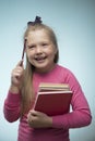 Little girl with a stack of books and a pencil in her hands on a blue background. Back to school and education concept Royalty Free Stock Photo