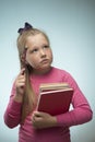 Little girl with a stack of books and a pencil in her hands on a blue background. Back to school and education concept Royalty Free Stock Photo