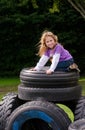 Little girl on stack of recycled tires