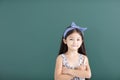 little girl stand before empty chalkboard