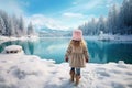 little girl stand in front of blue frozen lake in winter