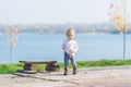 Little girl stand near a wood bench against the background of an autumn river Royalty Free Stock Photo