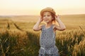 Little girl standing on the agricultural field at evening time. Conception of summer free time