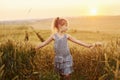 Little girl standing on the agricultural field at evening time. Conception of summer free time