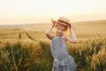 Little girl standing on the agricultural field at evening time. Conception of summer free time