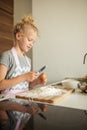 Little girl standing at crop mother and cracking egg to flour on kitchen. Royalty Free Stock Photo