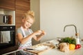 Little girl standing at crop mother and cracking egg to flour on kitchen. Royalty Free Stock Photo