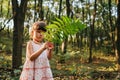 Little girl standing in the forest with ferns