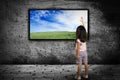 Little girl standing in front of a large monitor