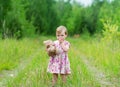 Little girl standing in grass holding large teddy bear. Royalty Free Stock Photo
