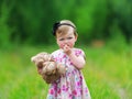 Little girl standing in grass holding large teddy bear. Royalty Free Stock Photo