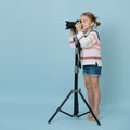 Little girl standing on her toes looking in the camera on tripod, taking picture Royalty Free Stock Photo