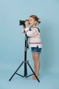 Little girl standing on her toes looking in the camera on tripod, taking picture Royalty Free Stock Photo