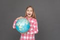 Freestyle. Girl standing isolated on grey with globe looking camera msiling excited Royalty Free Stock Photo