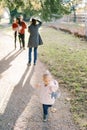 Little girl is standing on a path against the background of a photographer taking pictures of a married couple with a