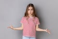 Little girl standing with raised hands and surprised indignant expression, asking what reason. Royalty Free Stock Photo