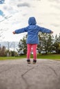 Little girl standing on a road in the park in spring. Child from behind Royalty Free Stock Photo