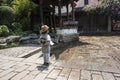 A little girl standing beside a scenic fountain looks sideways