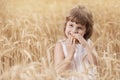 Little girl standing in a wheat field, baby bites the bread, smiling, concept
