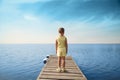 Little girl standing at wooden pier and looking to the sea. Royalty Free Stock Photo