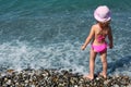 Little girl stands on beach, rear view